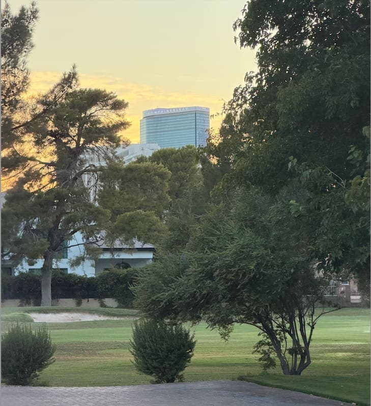 Mature trees along a Las Vegas Country Club Estates fairway at sunset, with the Las Vegas skyline behind them